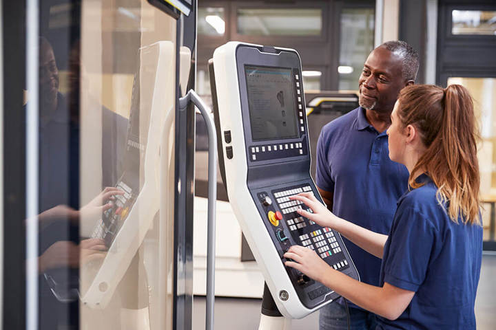 Engineer Showing Apprentice How To Use CNC Tool Making Machine