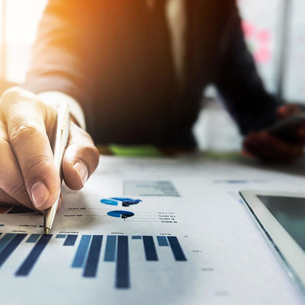 Close up Businessman hand holding pen and pointing at financial paperwork.