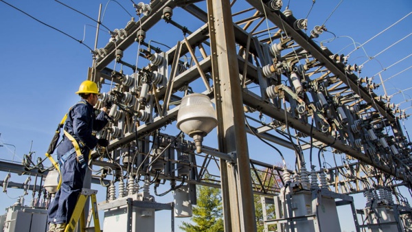 Electrician in the yellow hat examining a power microgrid system