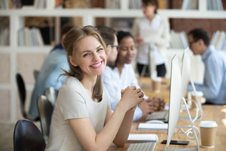 Female employee smiling in front of her computer.